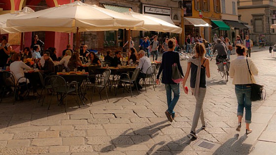 three women walking past a sidewalk cafe in Parma, Italy