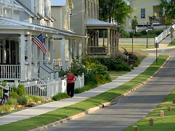 two women visiting, one on her porch and the other leaning against a frontage fence on a street at the Waters, Pike Road, Alabama