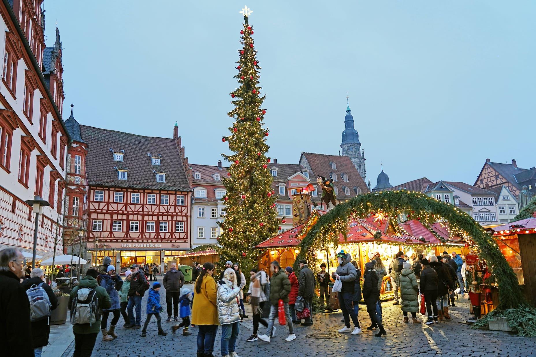 People stand at the festively lit Christmas market in Coburg.