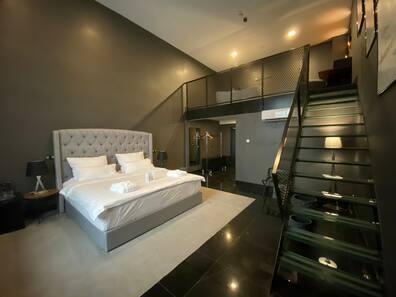 In the Black Hotel, from a room with a large box spring bed, a glass staircase leads directly to a second floor where a freestanding bathtub is located.