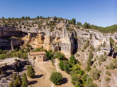 Hermitage in front of a rocky plateau.