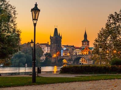 The riverside in Prague's Old Town with Charles Bridge and Vltava in the golden morning light.