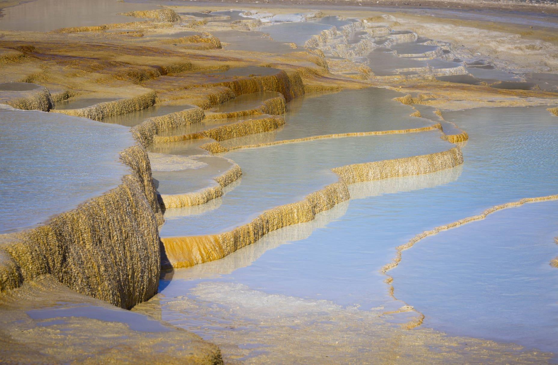 Orange rock forms from hot mineral springs cooling over the Badab-e Surt terraces.