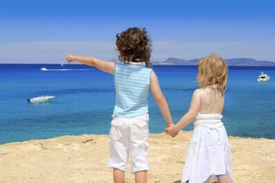 Two children standing on a paradise beach on the island of Formentera.