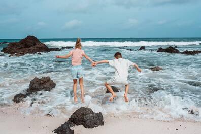 Two children jumping into the water at a volcanic beach on the Canary Islands.