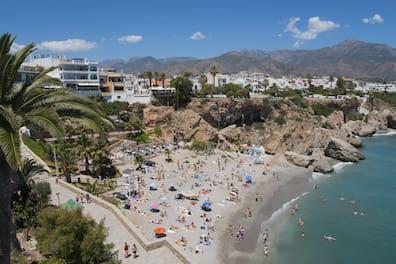 A crowded beach with crystal-clear water, many umbrellas, and people at Costa del Sol.
