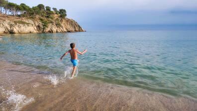 A boy runs into the water at a beach on Costa Brava in Spain.