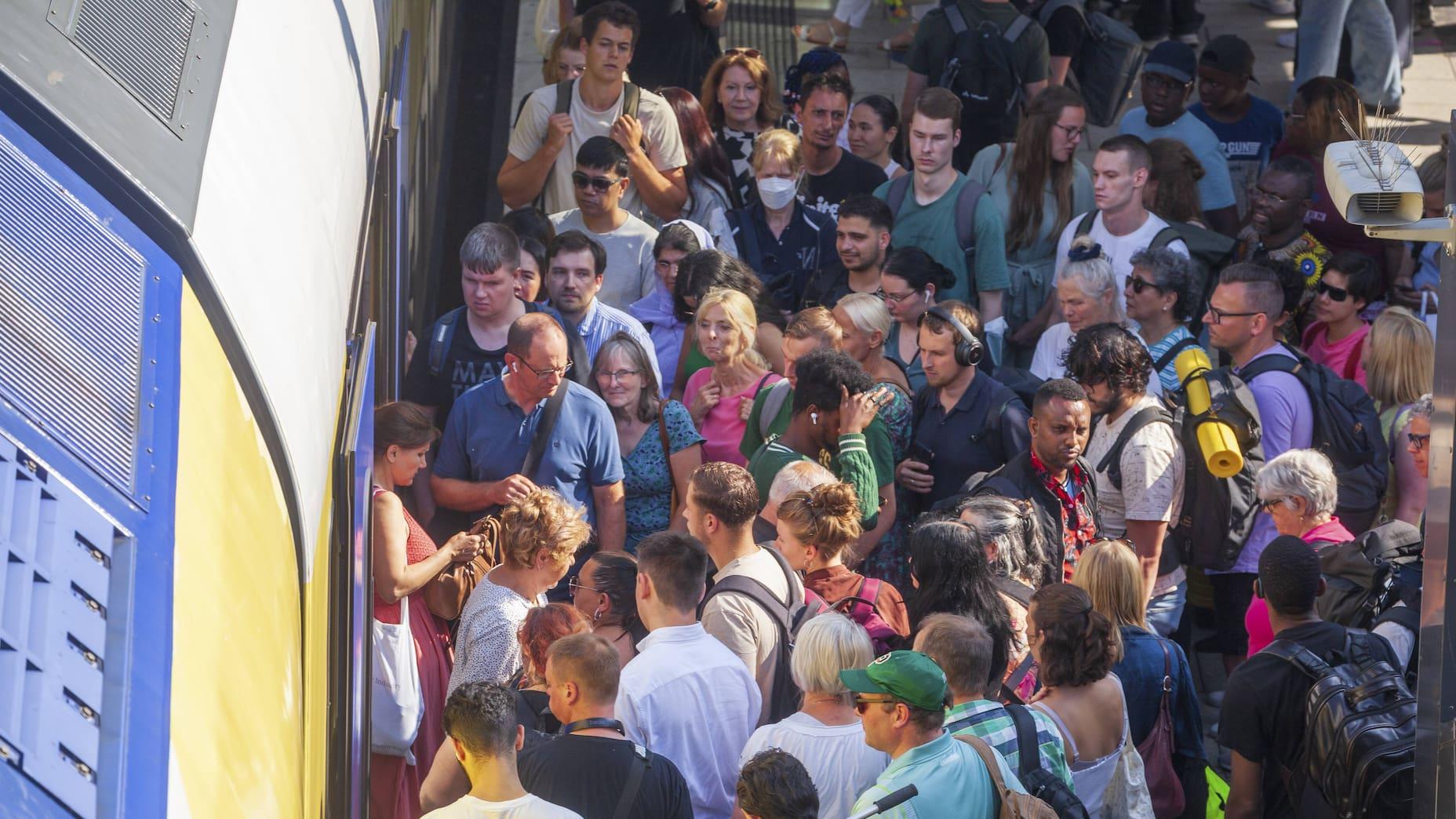 Many people standing on a platform in Hamburg, tightly packed in front of a commuter train.
