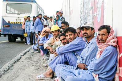 DUBAI - END OF WORKDAY Workers waiting for the bus. Hundreds of thousands of migrant workers are employed in construction in Dubai. Contractors must transport their workers in buses from the construction sites to their accommodations and back.