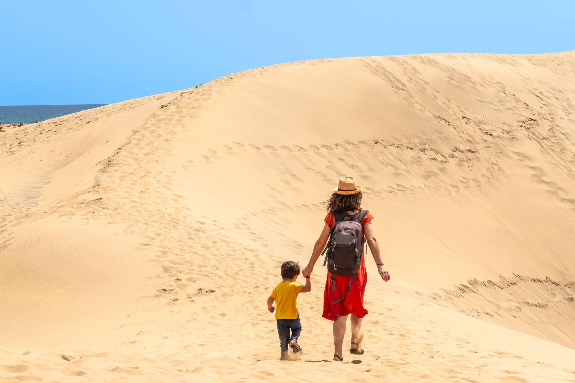 View of a mother with child walking on the dunes of Maspalomas on the island of Gran Canaria.