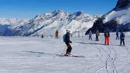 Skiers on a peak in Zermatt surrounded by a snowy mountain landscape