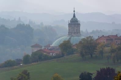 A domed roof in mist between trees and houses