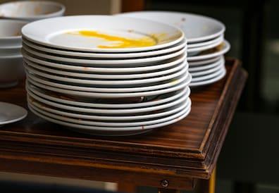 Used and stacked white plates on a table.