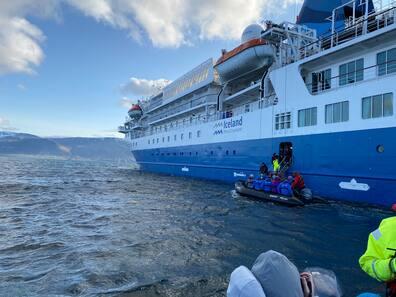 Passengers of the 'MS Seaventure' disembark through a door on the third deck into inflatable boats. The Zodiac trip goes to Drangey Island.