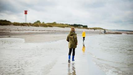 Two children running along the beach in rainy weather.
