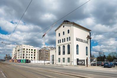View of a restored white building with the word 'Musoleum' on it.